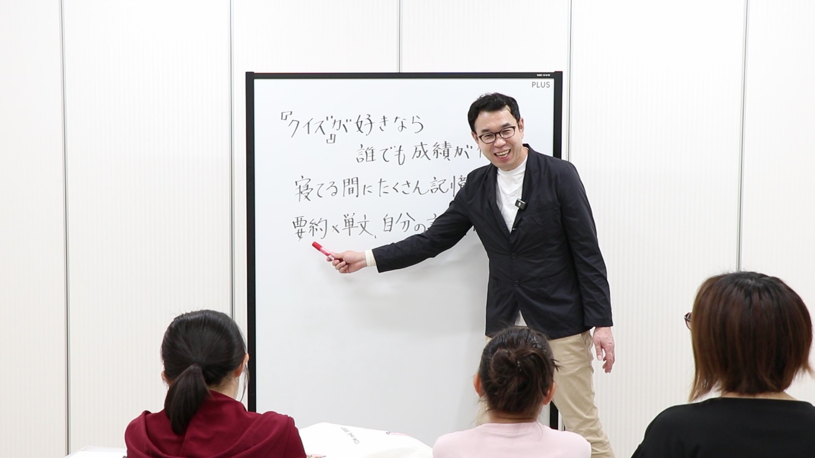 親子ゼミの様子。ホワイトボードを指しながら話す塾長と、参加している親子